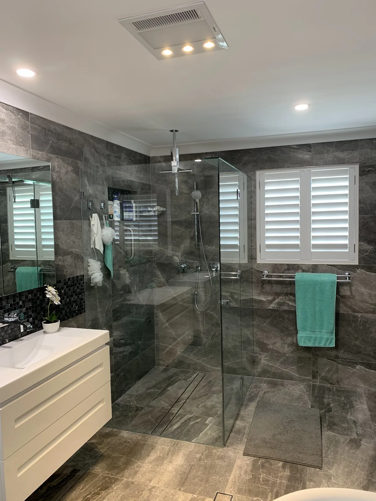 Bathroom with a ceiling heat lamp and exhaust unit, downlights and a large frameless shower