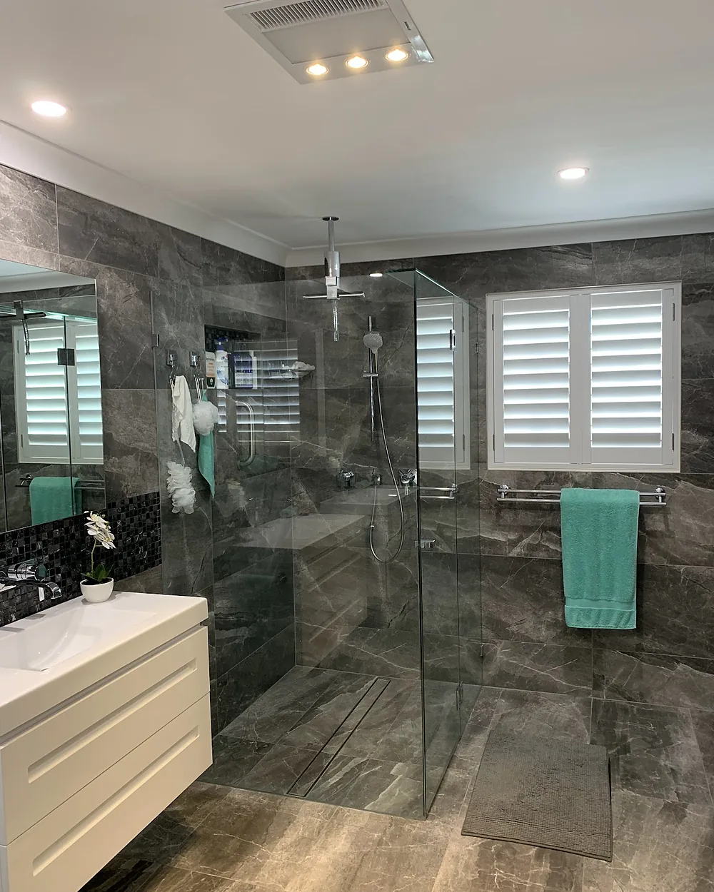Renovated bathroom with downlights, a heat lamp and exhaust fan and a frameless shower
