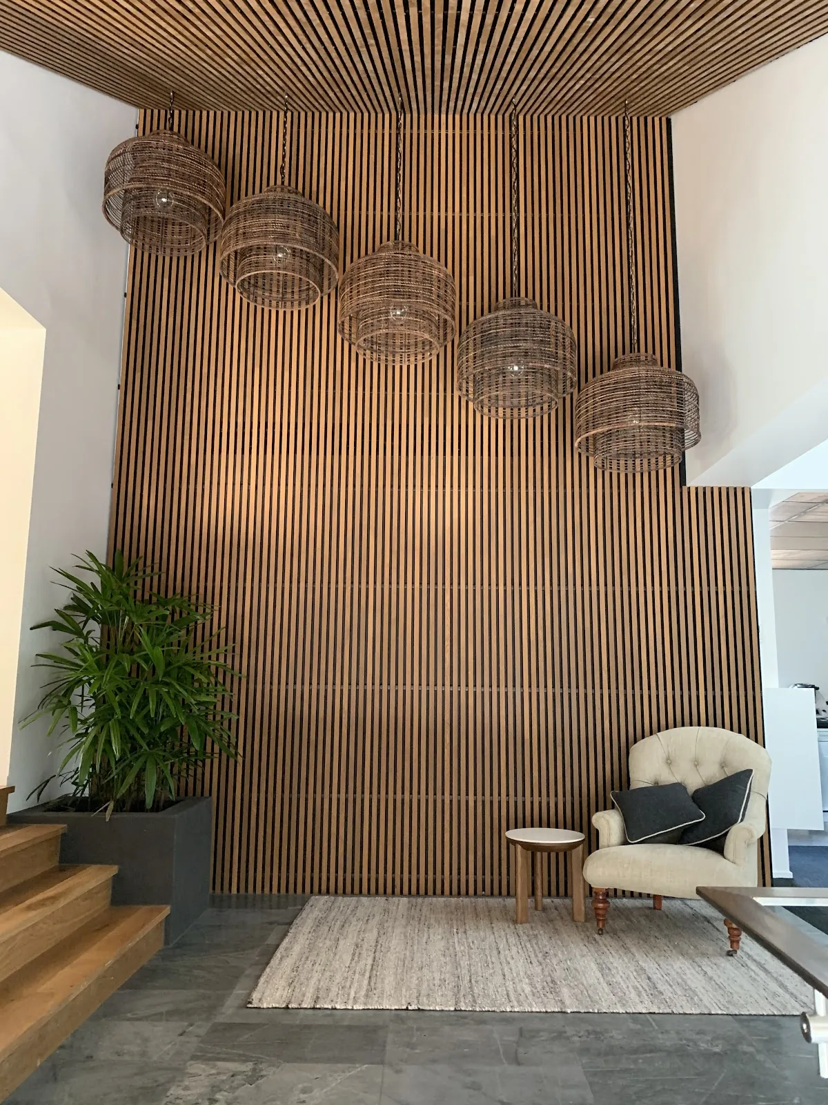 Five woven pendant lights stepped down a double-height timber feature wall